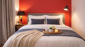 Ein Hotelzimmer mit Bett, Nachttisch, Lampe und Tablett mit Tassen und Blumen.