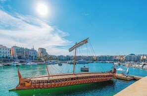 Un bateau en bois est amarré dans une marina, avec une vue sur la ville en arrière-plan.