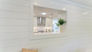 Una cocina moderna con armarios blancos, horno integrado y ventana sobre el fregadero.