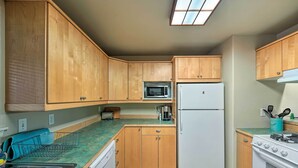 A kitchen with wooden cabinets, a microwave, a refrigerator, and a stove.
