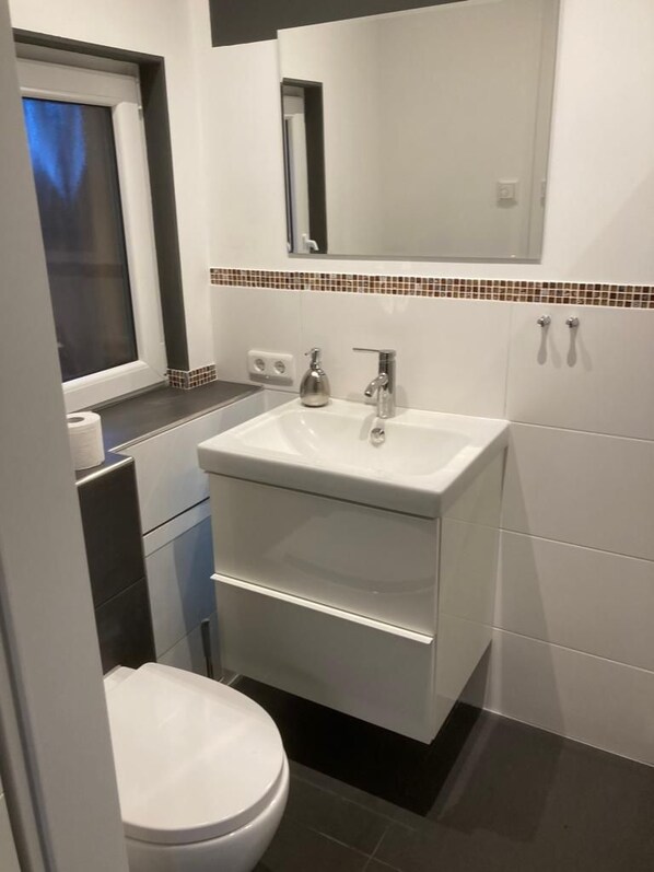 A modern bathroom with a white sink, mirror, and toilet. - Time for Two (Brandenburg an der Havel)
