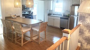A modern kitchen with white cabinets, a wooden island, wicker chairs, and pendant lighting. - 4 bedroom, 2 bath home with 3 porches, & steps from the beach in Atlantic Beach (Atlantic Beach)