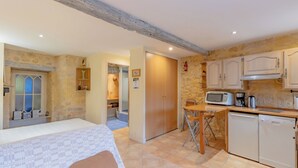 A compact room with a bed, a small dining area, and a kitchenette with basic appliances.