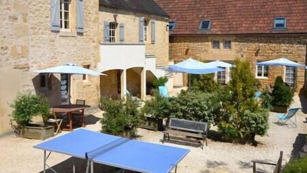 A courtyard with outdoor seating, umbrellas, and a table tennis table.