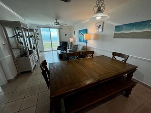 Un comedor amplio con una mesa y sillas de madera, un ventilador de techo y vistas al exterior a través de un ventanal.