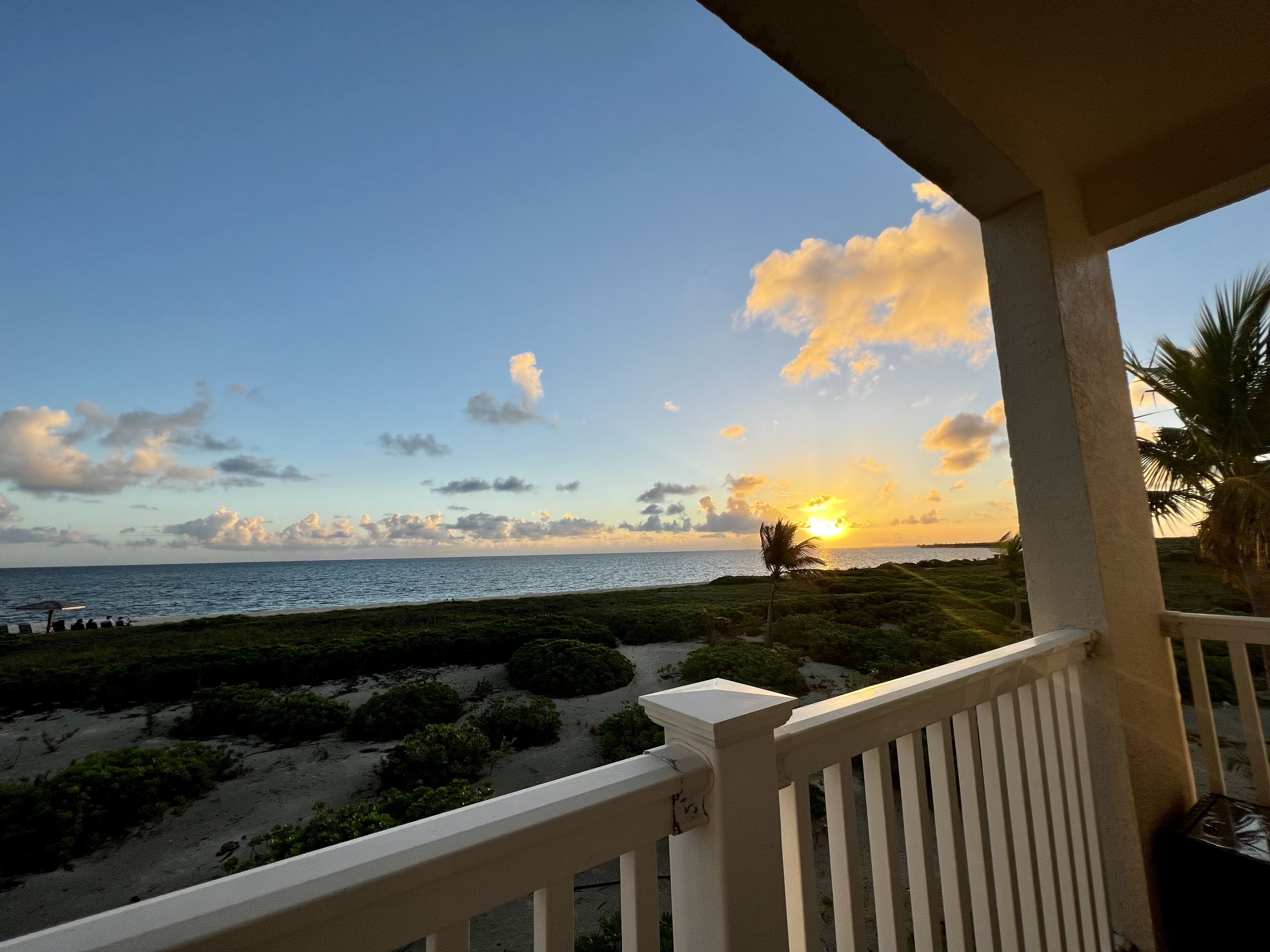 A balcony with a view of the ocean at sunset.