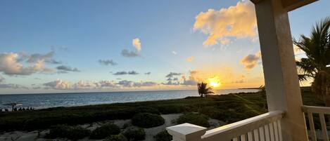 A balcony with a view of the ocean at sunset.