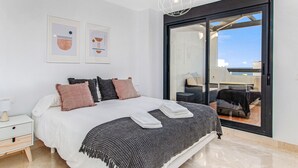 Ein modernes Schlafzimmer mit einem großen Bett, einem Nachttisch und Blick auf die Terrass'.