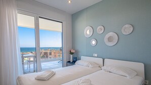 Et hotelværelse med to senge, en balkon med havudsigt og dekorative vægplader.