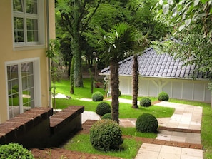 A well-maintained garden with a patio area, a small building with a tiled roof, and a brick wall. - Romantic villas right next to Schlössle Park, 2 minutes' walk to the beach (Kressbronn)