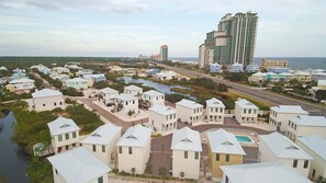 Un quartier résidentiel situé sur la côte, avec de nombreuses maisons à deux étages, une route principale et, au loin, un grand bâtiment d’hôtel.