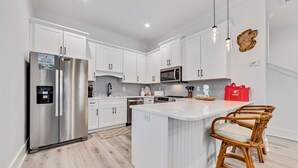 A modern kitchen with white cabinets, stainless steel appliances, and a central island with bar stools.