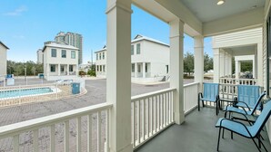 A covered outdoor area with a pool, white buildings, and blue chairs.