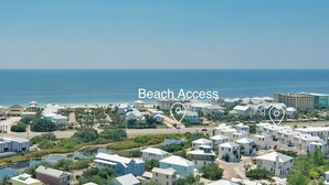 A coastal residential area with beach access, featuring a mix of single-story and multi-story houses, a clear view of the ocean, and a well-maintained landscape.