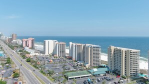 Un paisaje urbano costero con rascacielos, una playa y un estacionamiento.