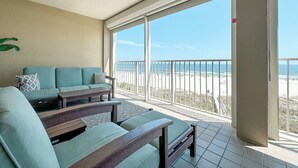 Un balcón con vistas a la playa, un sofá y una mesa.