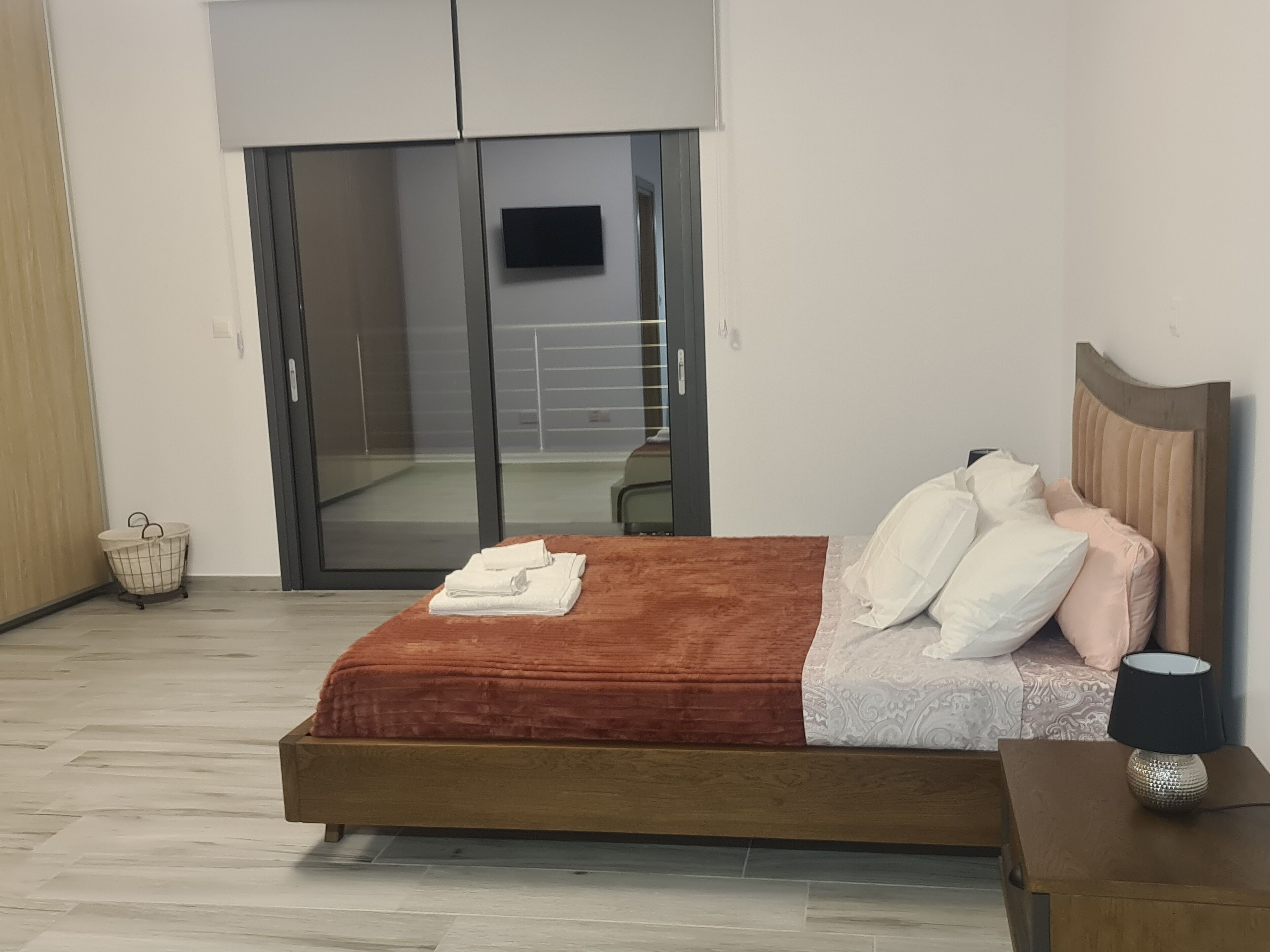 Una camera da letto con un letto, un comodino, una lampada, un tavolino e una porta scorrevole che dà su un balcone.