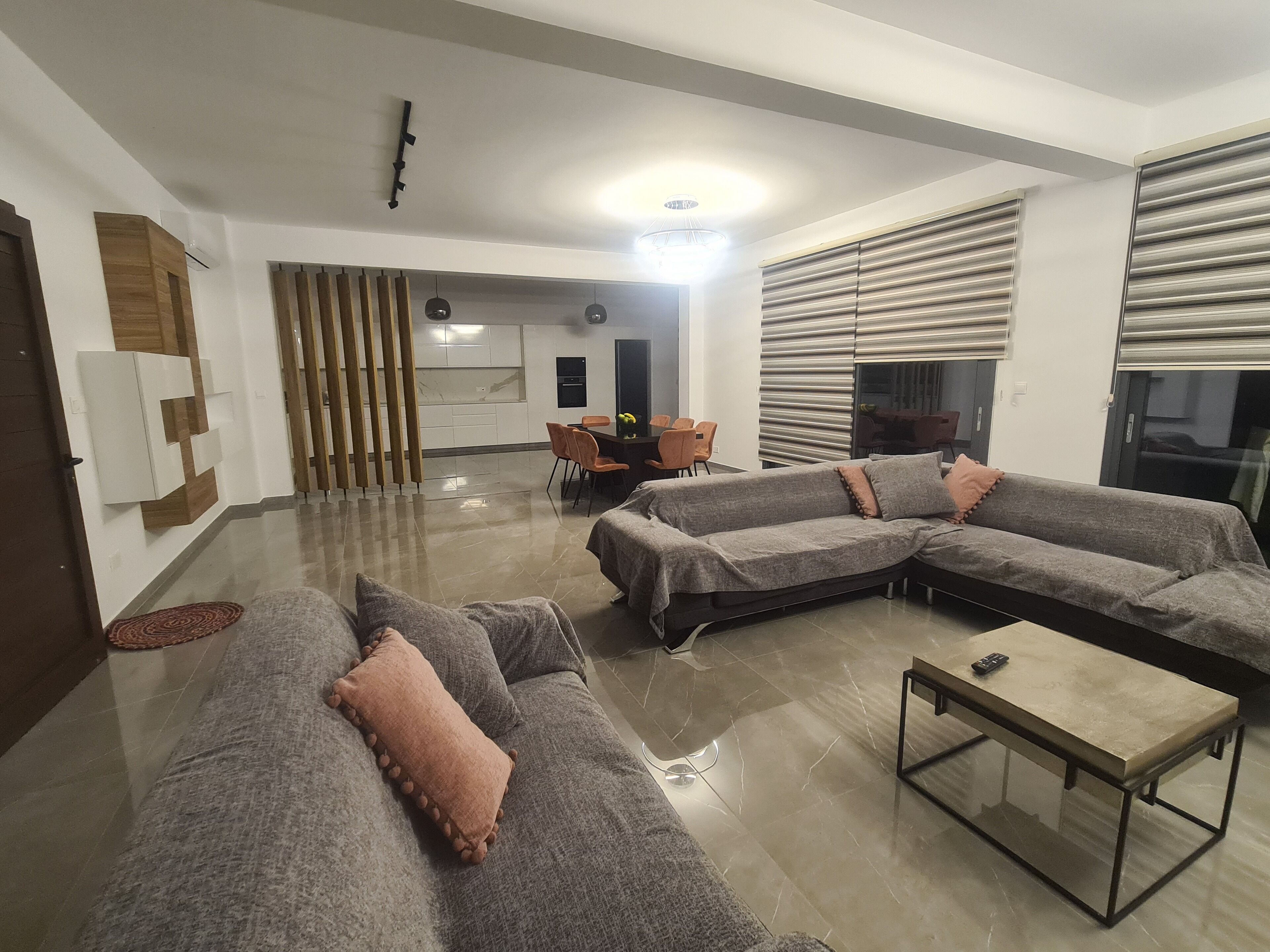 Ein modernes Wohnzimmer mit einer Eckcouch, einem Glastisch und einem Essbereich mit Tisch und Stühlen.