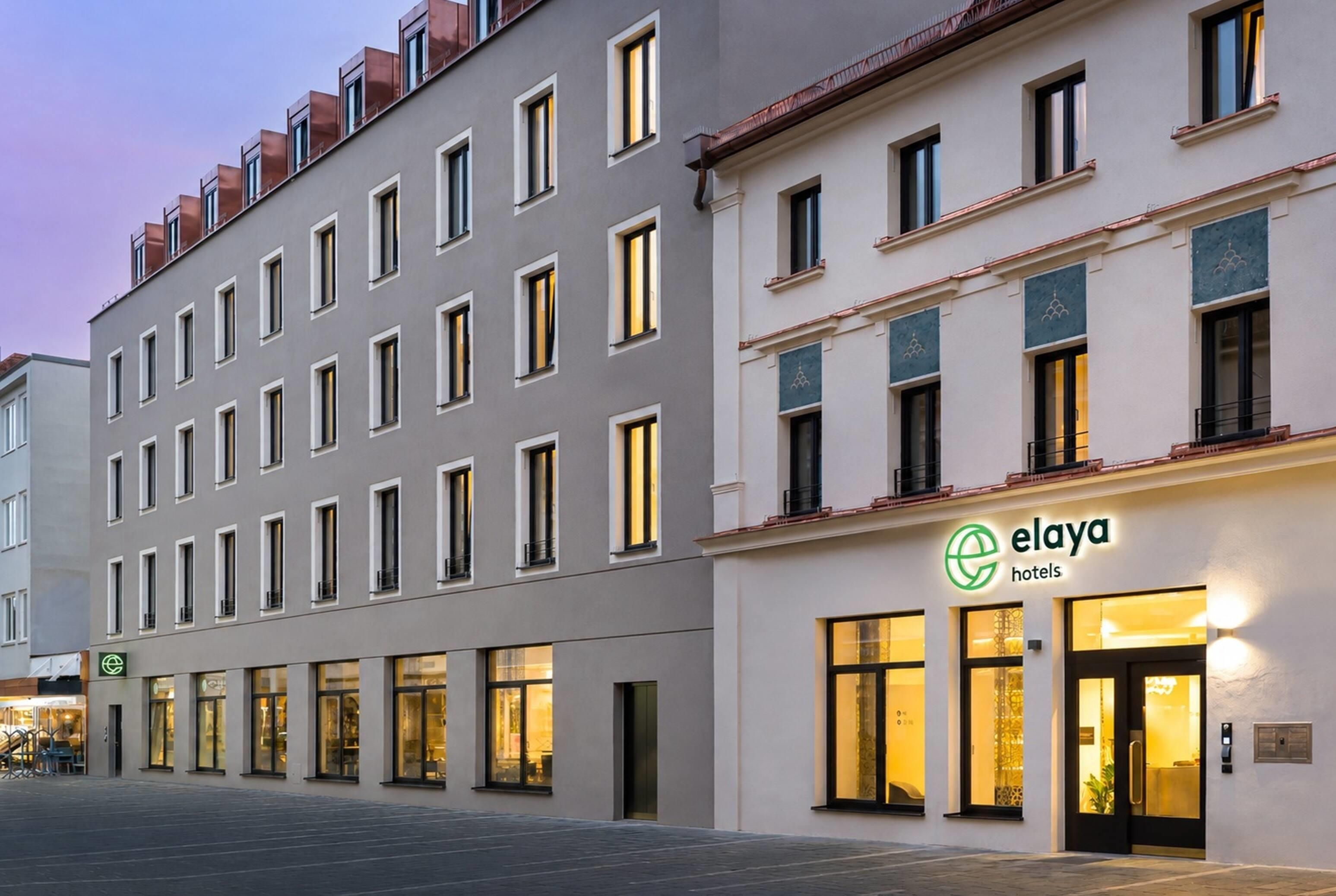Ein mehrstöckiges Hotelgebäude mit großen Fenstern und einem Schild für 'elaya hotels'.