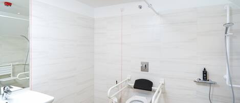 A modern bathroom with a white sink, a toilet with a black seat, and a shower area.