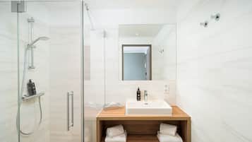 A modern bathroom with a glass-enclosed shower, a wooden vanity with a sink, and a mirror above the vanity.