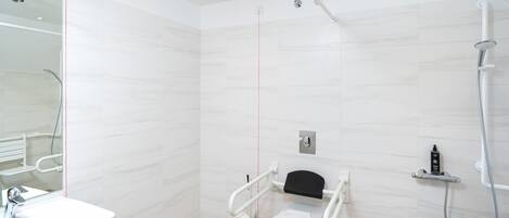 A modern bathroom with a white toilet, a shower, and a sink.