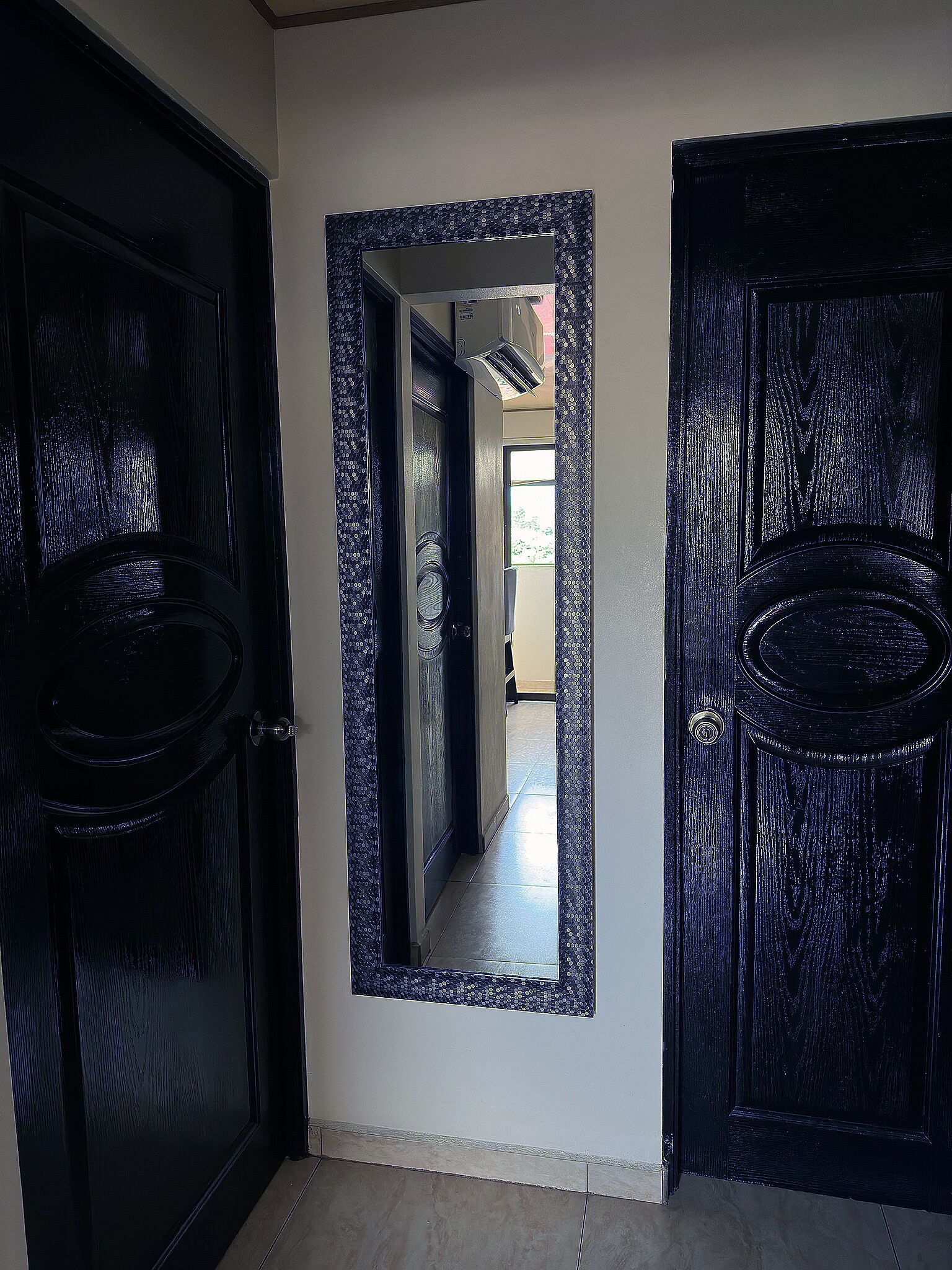 A hallway with black doors and a large mirror.