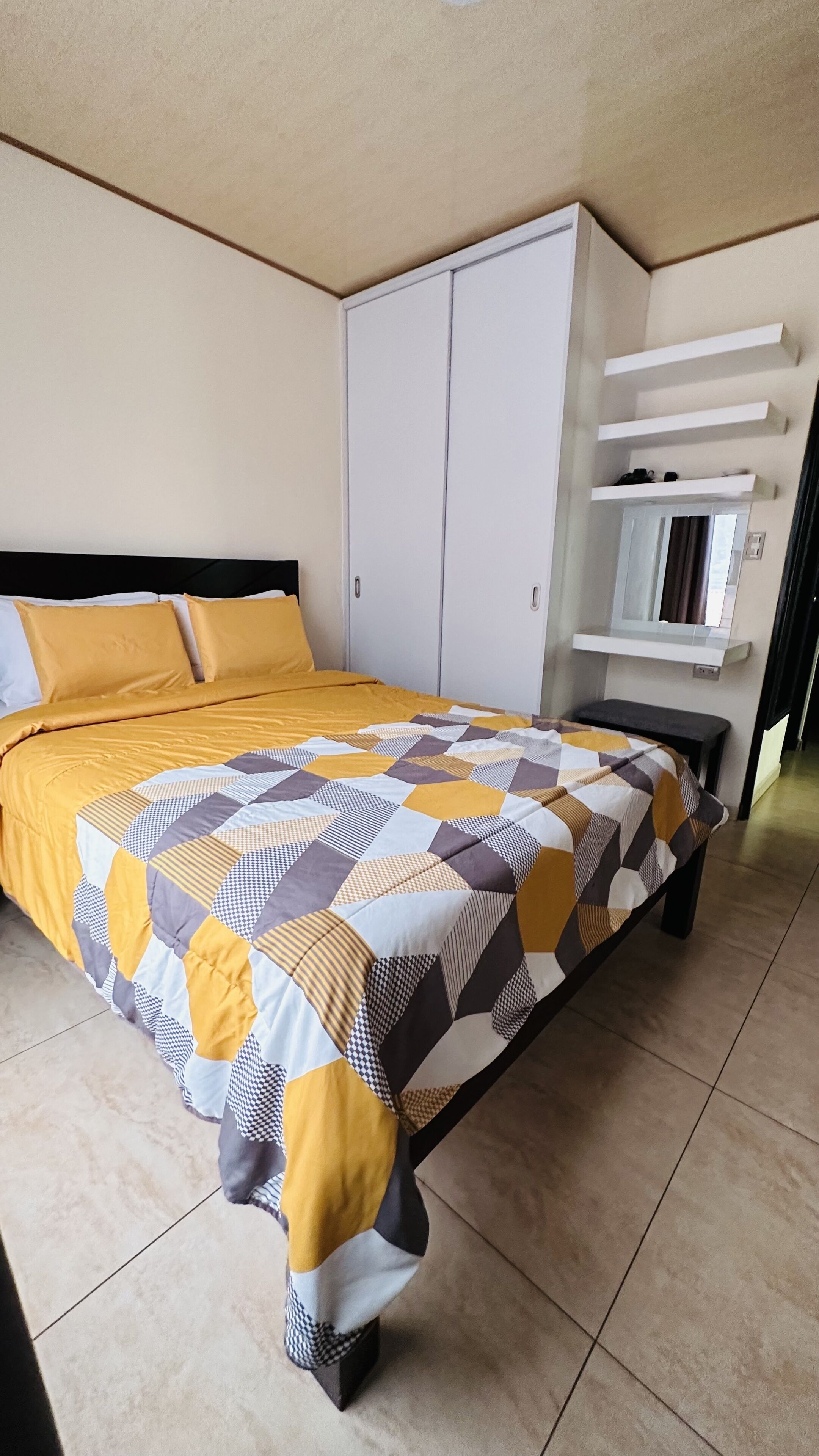 A bedroom with a bed, a wardrobe, a mirror, and a shelf with shoes.
