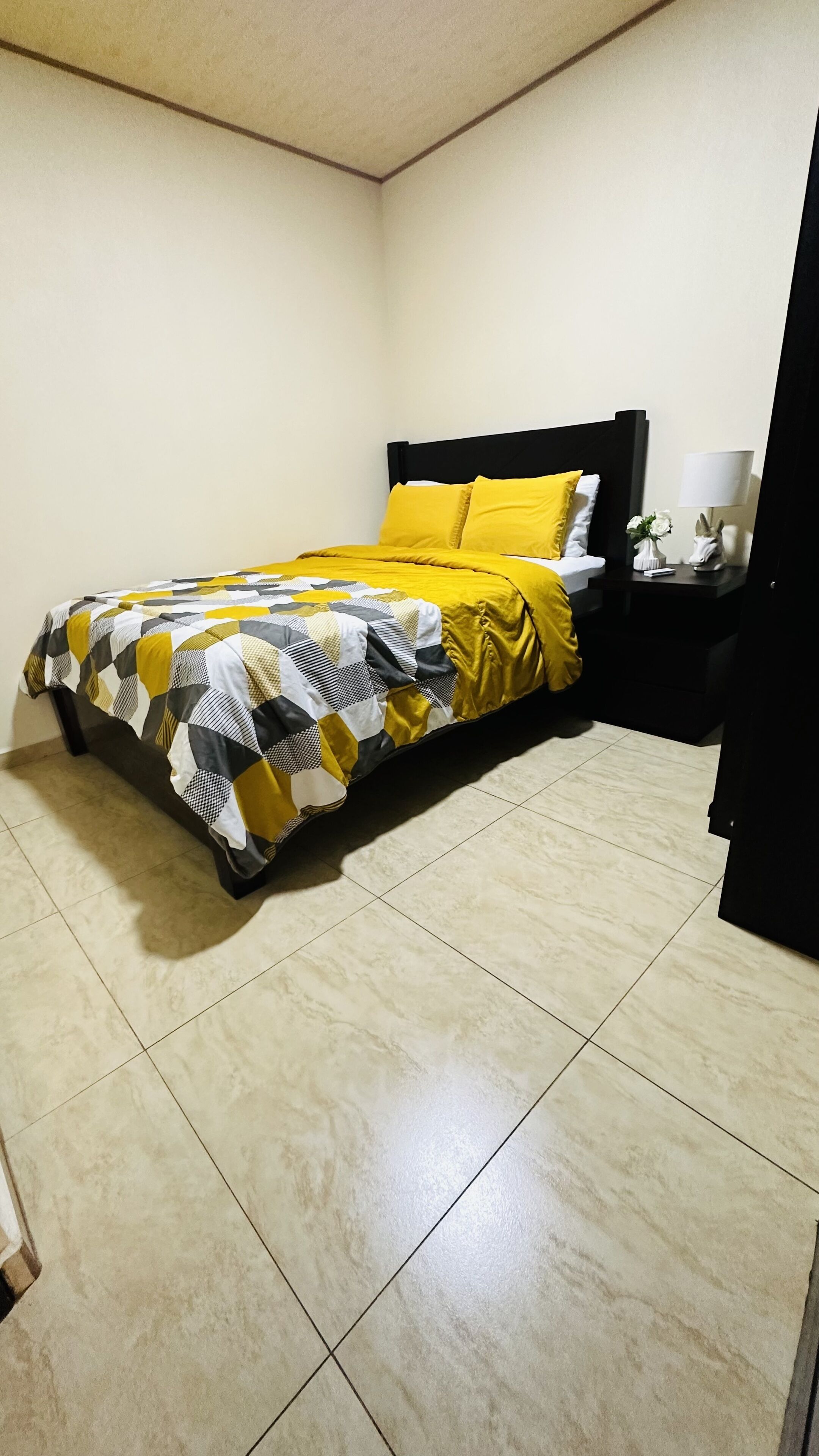 Un dormitorio con una cama, una mesita de noche y una lámpara.