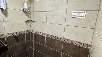 Une salle de bain équipée d’une douche, d’un porte-serviettes et d’un sèche-mains.