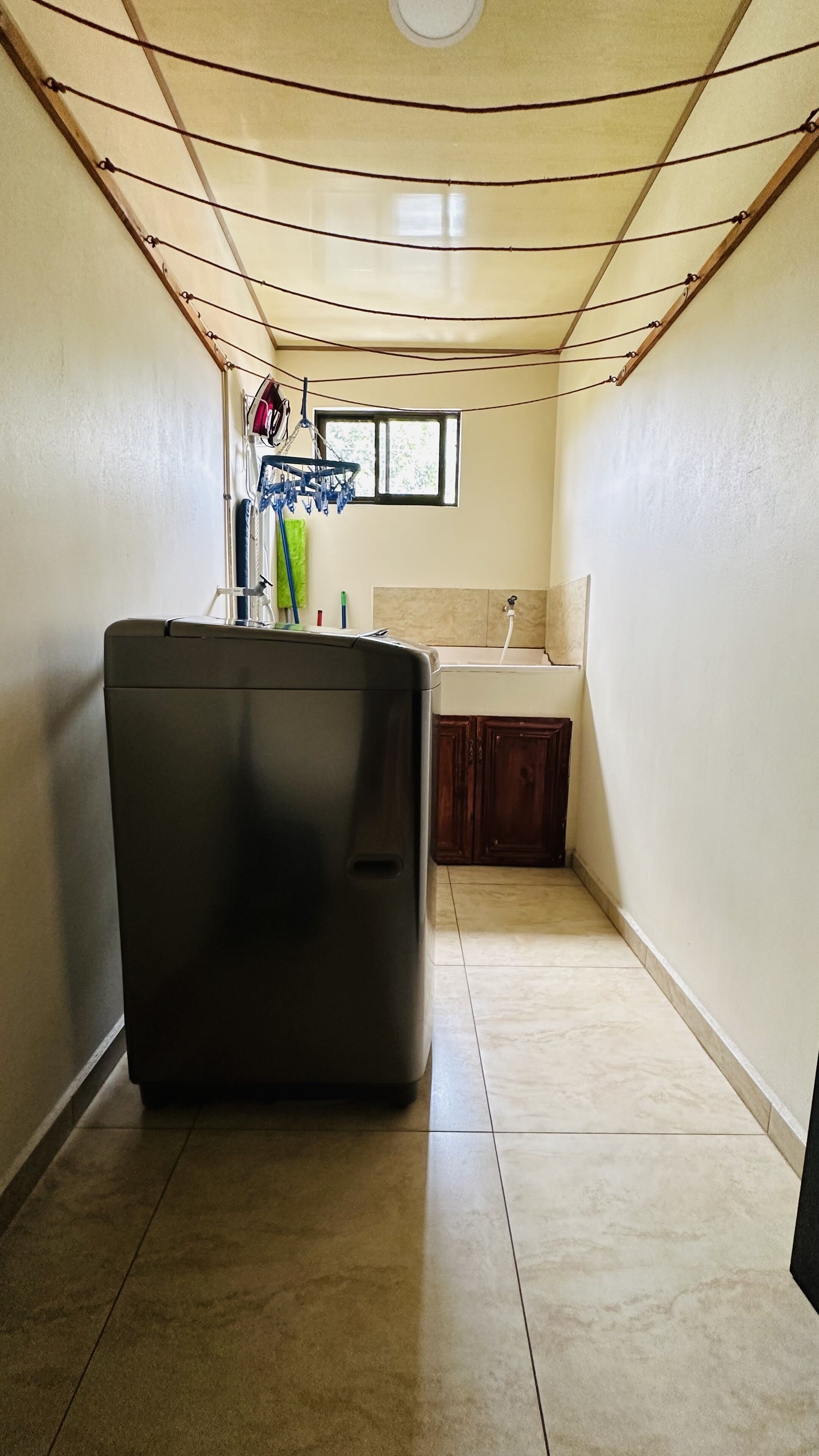 A compact kitchen with a washing machine, a small window, and a tiled floor.