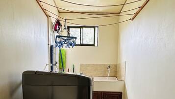 A compact kitchen with a washing machine, a small window, and a tiled floor.