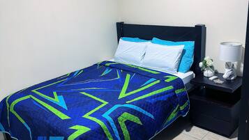 A bedroom with a bed, a nightstand, and a lamp.