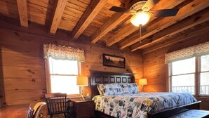 Ein Schlafzimmer einer Holzhütte mit einem Bett, einem Schreibtisch und einem Stuhl.