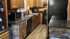 Eine Küche mit Holzschränken, Granitarbeitsplatten, einem Edelstahlkühlschrank und einem Geschirrspüler.