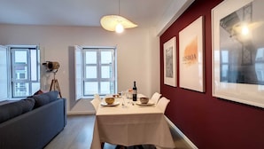 A dining area with a table set for two, a sofa, and a tripod-mounted camera.