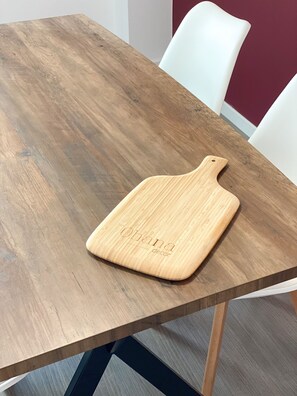 Een houten tafel met een snijplank erop.