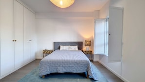 A bedroom with a bed, nightstands, a lamp, and a wardrobe.