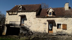 A stone building with a tiled roof, a small balcony, and a wooden door. - Country house with lots of outdoor space (Beauregard)