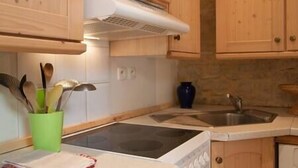Una cocina con armarios de madera, una estufa, un fregadero y un recipiente verde con utensilios.