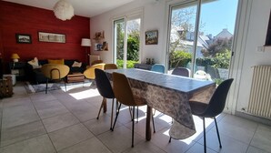 Een eetruimte met een marmeren tafel, moderne stoelen, een rode accentmuur en uitzicht op groen.
