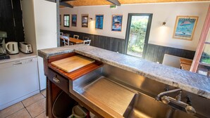 A kitchen with a built-in dishwasher, a wooden countertop, a sink, and a window overlooking the outdoors. - Le Pressoir - Domaine de Geffosses (PONT L EVEQUE)