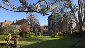 A park with a pond, a playground, and a building with a tower. - Villa Marguerite (Saint-Omer)