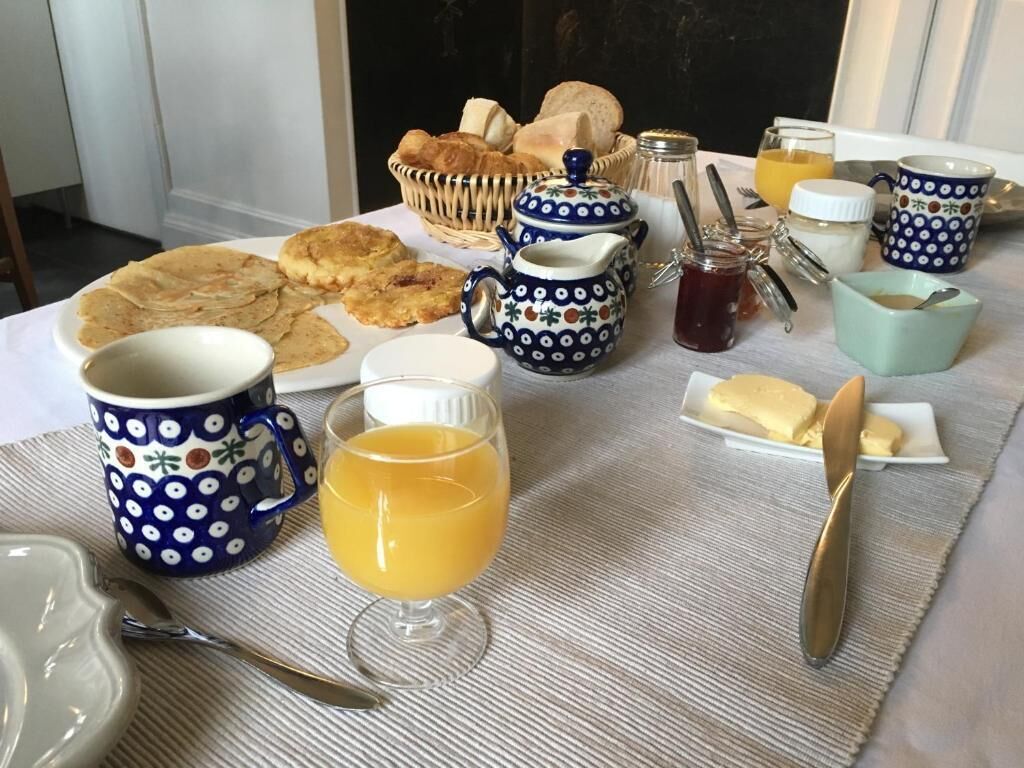A breakfast table with various food items, including pastries, bread, and a teapot.