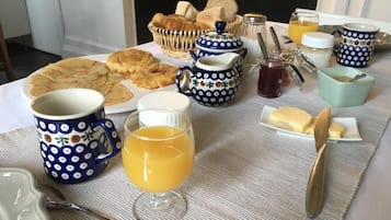 A breakfast table with various food items, including pastries, bread, and a teapot.