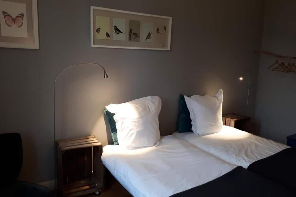 Une chambre à coucher comprenant un lit, deux tables de chevet, une lampe sur pied et des œuvres d’art murales.