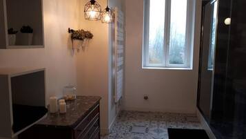 Une salle de bain avec un carrelage décoratif, une fenêtre, une douche et un miroir.