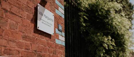 A brick wall with a sign for Villa Marguerite, indicating it is a hotel with a bedroom and breakfast.