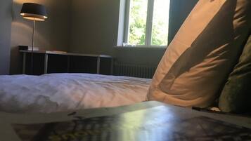 A bedroom with a bed, pillows, a lamp, and a window.