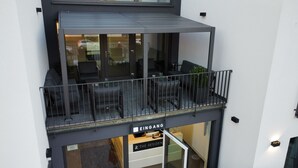 A modern building with a balcony featuring outdoor seating and a railing. - The Residences - Apartments Frankfurt (Offenbach am Main)